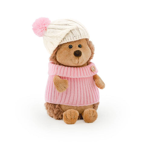 Front facing photo of a plush hedgehog soft toy, dressed in a pink jumper and white woolly hat with a pink pom pom. 